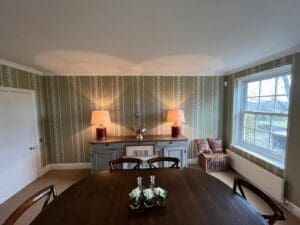 green wallpaper hung in dining room around a window