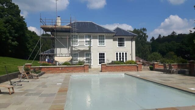 Large house painting exterior brick walls in sage green masonry paint