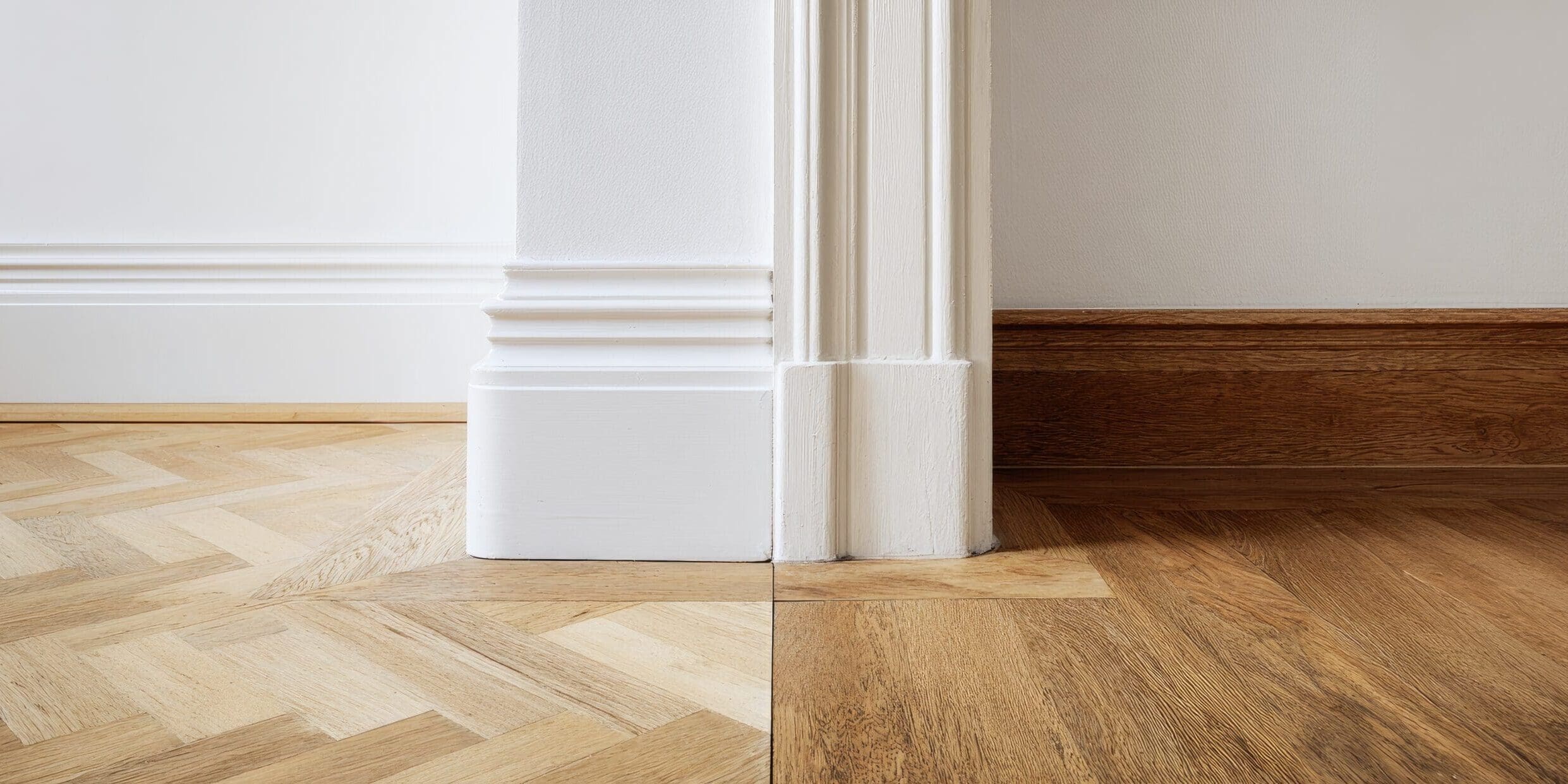 Interior corner with white skirting boards and herribone floors